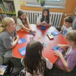 Dzieci przy stoliku wykonują pracę plastyczną